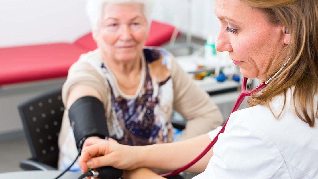 Eine Ärztin misst den Blutdruck einer älteren Patientin. 