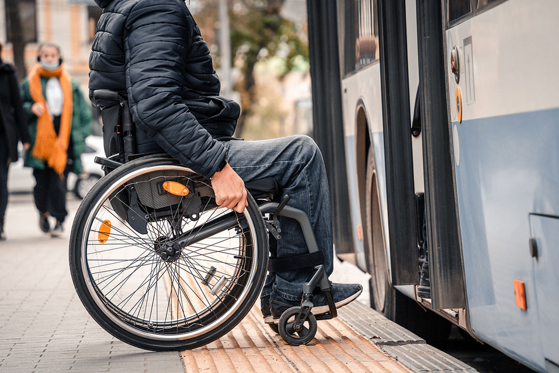 Mann im Rollstuhl vor geöffneter Bustür