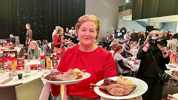 Eine Frau mit zwei Tellern voller Essen in den Händen.