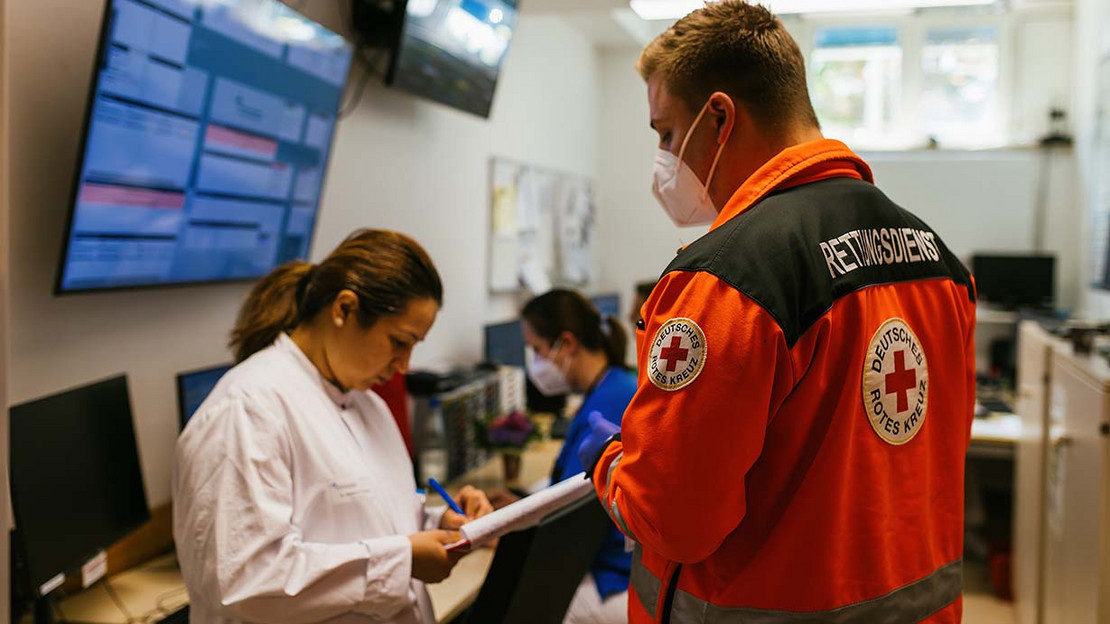 In einer Notaufnahme steht ein Mitarbeiter eines Rettungsdienstes und macht eine Übergabe an die Mitarbeitenden der Klinik.